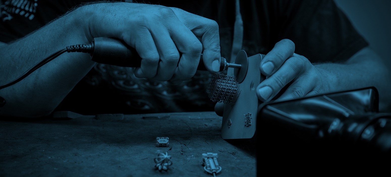 a metal 3D printing technician removes support structures from a DMLS part